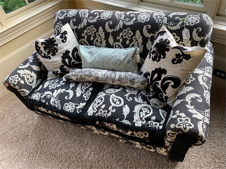 Black and white patterned loveseat with decorative pillows