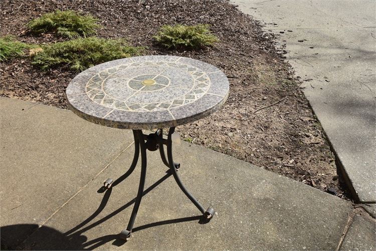 Small, round tile top patio table on molded iron base.