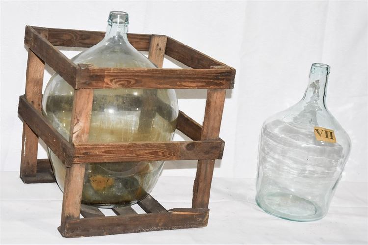 Two (2) Large Glass Jugs One With Accompanying Wooden Crate