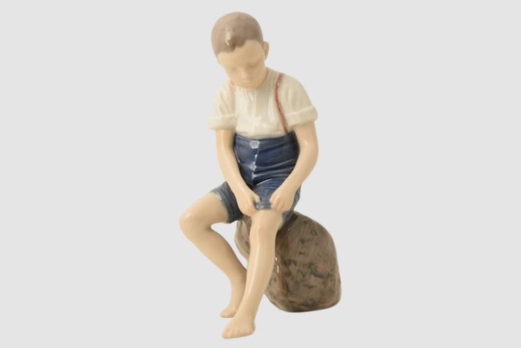 Bing & Grondahl Boy sitting on stone rolling up trousers