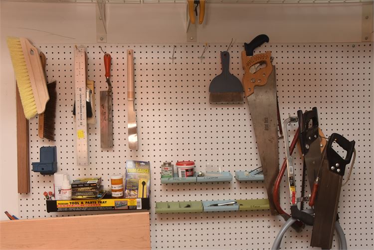 Pegboard Wall with Various Tools: Brushes, Saw and Scraper.